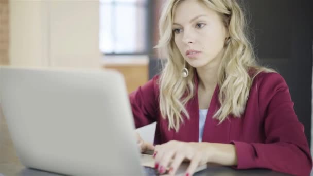 Schöne junge blonde Geschäftsfrau tippt am Laptop bei der Arbeit — Stockvideo