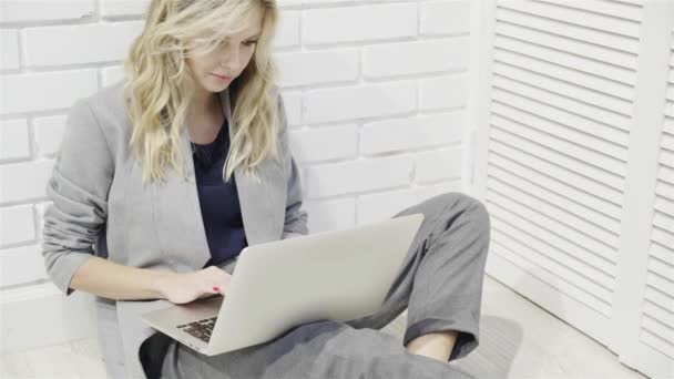 Vacker affärskvinna i grå maskinskrivning på laptop på golvet — Stockvideo