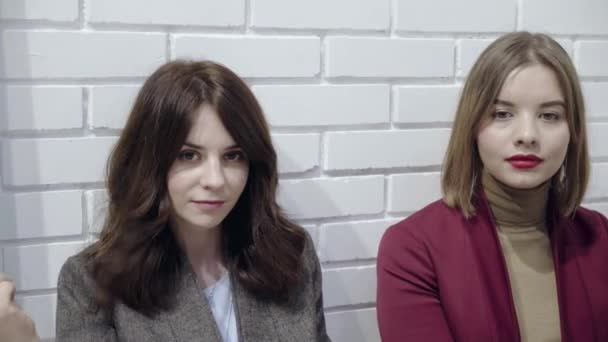 Tres mujeres jóvenes en trajes haciendo caras graciosas cerca de una pared blanca — Vídeo de stock