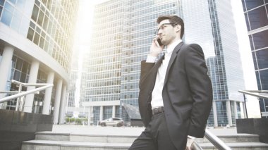 Genç bir işadamı konuşuyor ve telefonda merdivenlerde gülümseyen