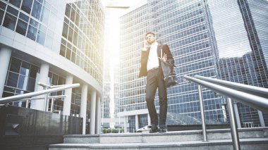 Genç bir işadamı merdivenlerde telefonda bir soru çözdü