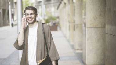 Giyinmiş adam rahat kıyafetler gülüyor ve telefon görüşmeleri