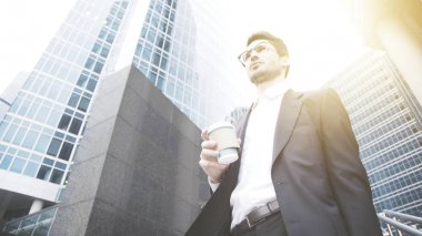 Genç bir işadamı bir fincan kahve sokakta tutuyor