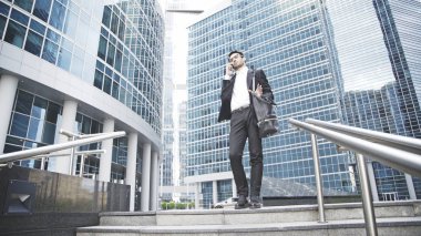 Genç bir işadamı merdivenlerde telefonda bir soru çözdü