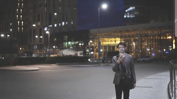 Un joven al aire libre con un móvil por la noche — Foto de Stock