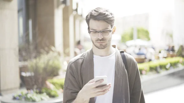 A young serious man scrolls the phone