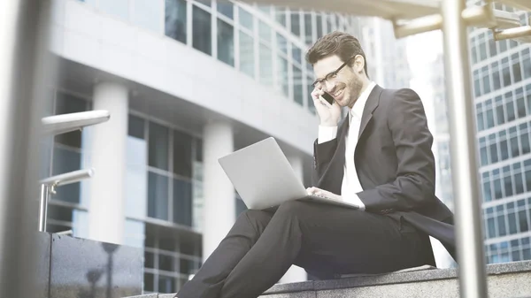 Zakenman met een laptop met een oproep in de openlucht — Stockfoto