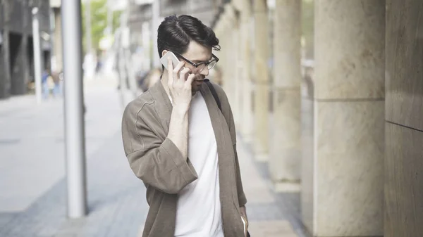 Un giovane uomo vestito con abiti casual che parla al telefono — Foto Stock