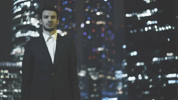Um jovem empresário sério vestido com um terno preto à noite — Fotografia de Stock