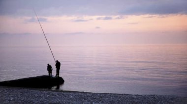Baba ve oğul deniz sahilinde Balık tutma