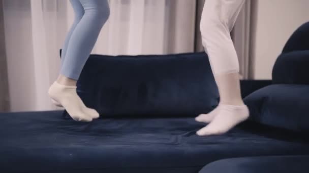 Duas meninas irreconhecíveis em leggings pulando juntos em uma cama king size — Vídeo de Stock