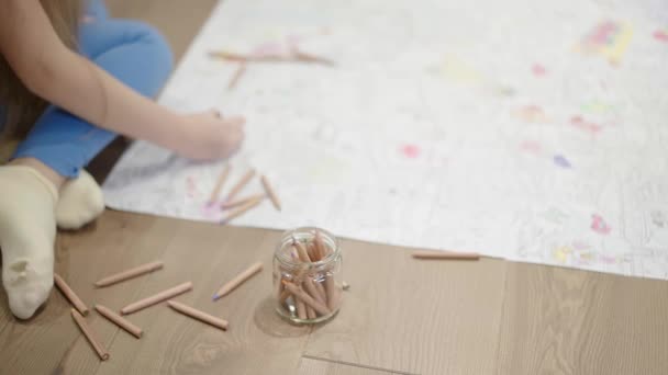 Una niña pequeña para colorear una imagen grande en el suelo — Vídeo de stock