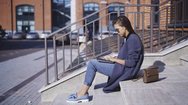 Una giovane ragazza con gli occhiali da sole sta lavorando sulle scale all'aperto — Foto Stock