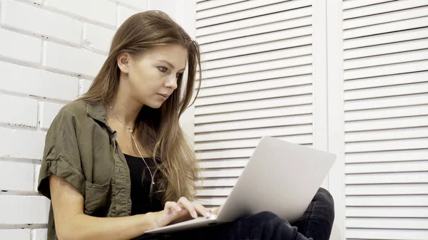 Genç konsantre kız öğrenci bir closeup katta oturan dizüstü bilgisayar ile çalışma — Stok fotoğraf
