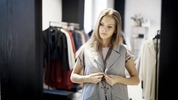 Une jeune fille essaie une veste grise dans un magasin — Photo