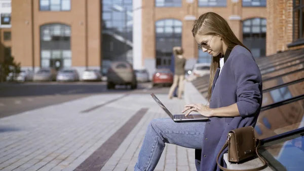 Een mooi meisje in zonnebril is werken met een laptop outisde — Stockfoto