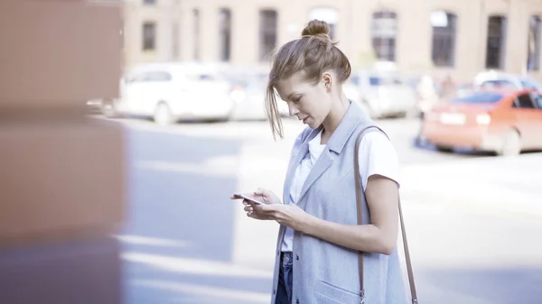 Een jong meisje aan het typen is op de telefoon buiten — Stockfoto