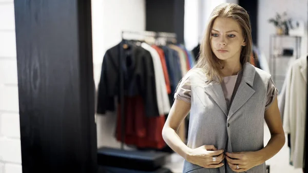 Une jeune fille essaie une veste dans un magasin — Photo