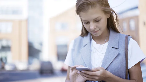 Een lachende gelukkig meisje alleen gekleed in een jas in een telefoon te typen — Stockfoto