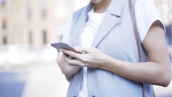 Een close-up van vrouwelijke handen met een telefoon tryping — Stockfoto