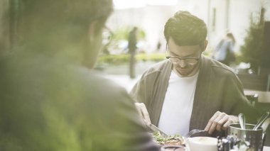Yakışıklı bir sakallı adam açık havada café'de salata yiyor