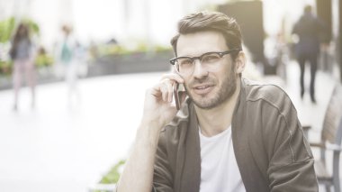 Gülümseyen genç adam bir telefon sahip telefonda konuşurken bir closeup