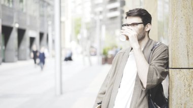 Yakışıklı bir adam kahve ayakta sokağın köşesinde içme