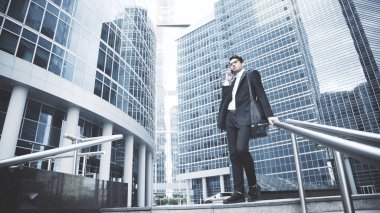 Genç bir işadamı merdivenlerde telefonda konuşuyor