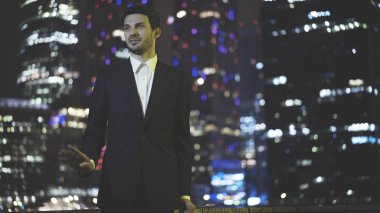 Gece siyah bir takım elbise giymiş bir konuşan genç iş adamı