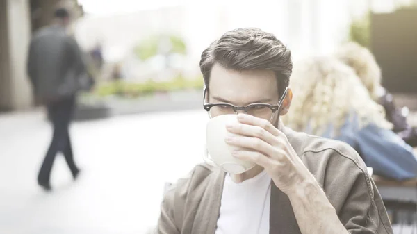 Un primer plano del hombre sentado en la cafetería bebiendo café al aire libre — Foto de Stock