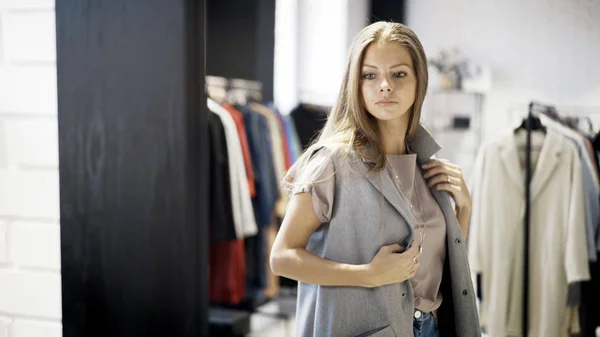 Une jeune fille essaie une veste grise dans un magasin — Photo