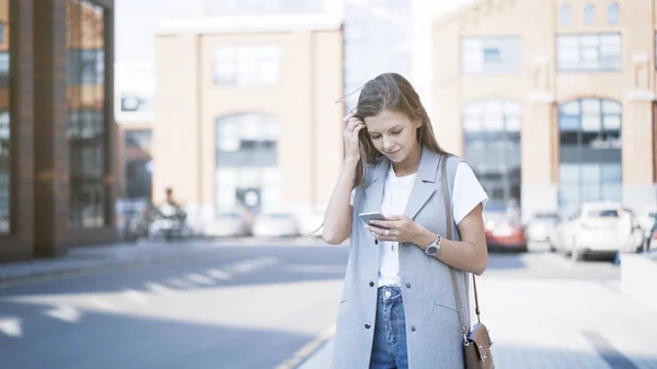 Een jong meisje alleen gekleed in een jas in een telefoon te typen — Stockfoto