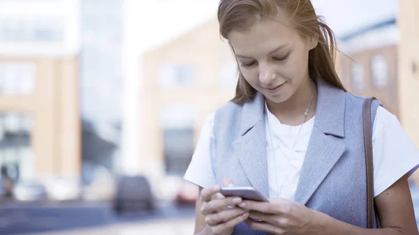 Een lachende gelukkig meisje alleen gekleed in een jas in een telefoon te typen — Stockfoto