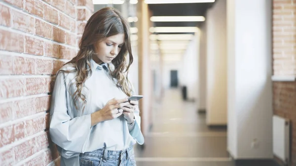 Jonge vrouw kijken naar telefoon bij de opbouw van de corridor — Stockfoto