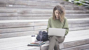 Bir kız ile bir dizüstü bilgisayar çalışma merdivenlerde oturan