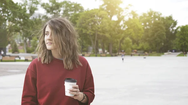 Una giovane ragazza bruna casuale carina sta bevendo caffè all'aperto al mattino — Foto Stock