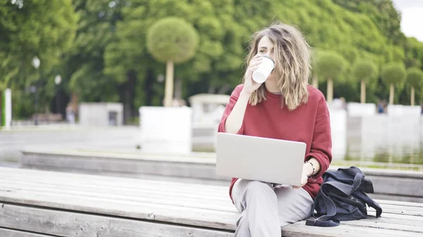 Een casual jong meisje in het park met een laptop — Stockfoto