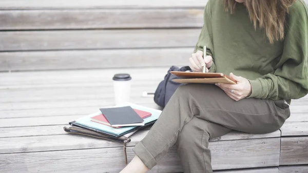 Una ragazza è seduta sulle scale a lavorare con un tablet — Foto Stock