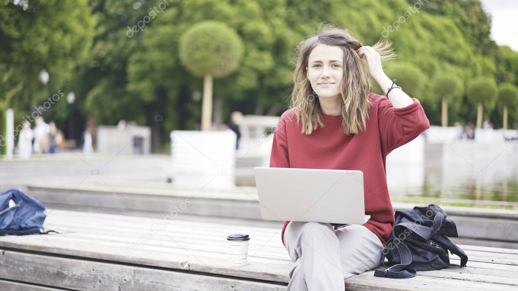 A casual young girl in the park with a laptop