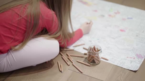 One unrecognizable little girl coloring a large picture on the floor — Stock Video