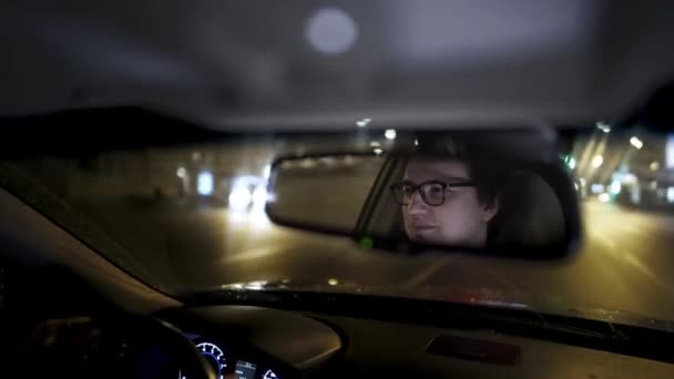 Joven hombre de negocios en gafas conduciendo a casa desde el trabajo hasta tarde en la noche — Vídeo de stock