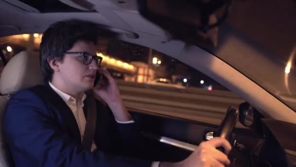 Podnikatel, řízení auta v noci a mluví o jeho nebezpečí smartphone — Stock video