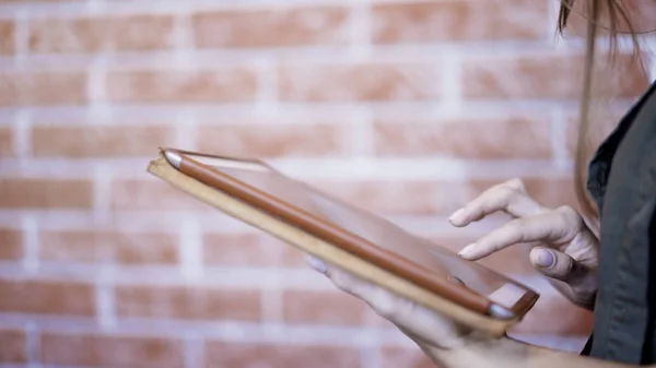 Een jong meisje met behulp van moderne digitale tablet bakstenen muur achtergrond — Stockfoto