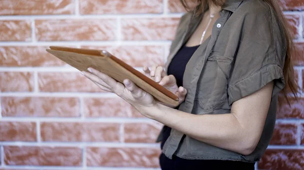 Una giovane ragazza utilizzando moderno digitale tablet mattone muro di sfondo — Foto Stock