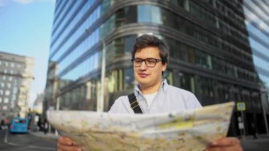 Haritalı bir adamın yol ortasında durup binalara bakarken çekilen görüntüsü.