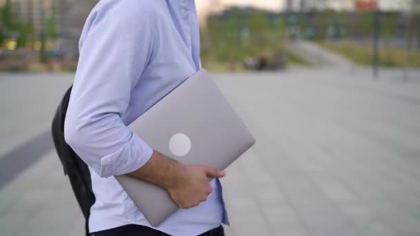 Профіль середній знімок чоловіка в синій сорочці, що йде з ноутбуком, без обличчя — стокове відео