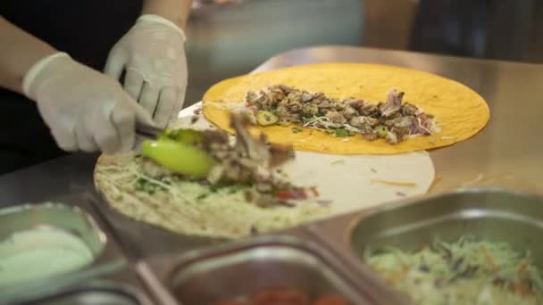 Prise de vue à la main de mains de chef en gants blancs faisant deux donateurs en pita — Video