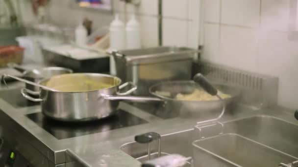 Fazekak és serpenyők közelsége a tűzhelyen a konyhában — Stock videók