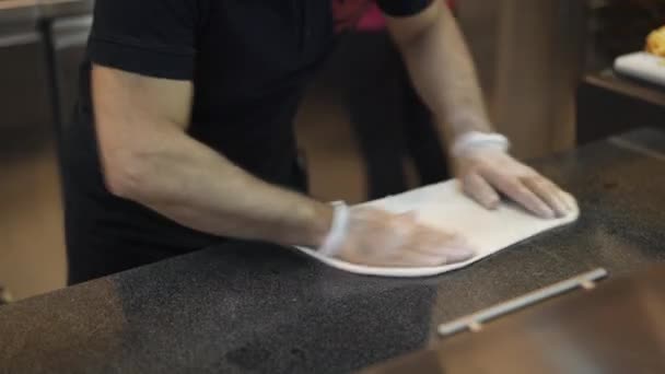 Cocinar estira el borde de la masa de pizza en la mesa de mármol en la cocina oscura — Vídeos de Stock