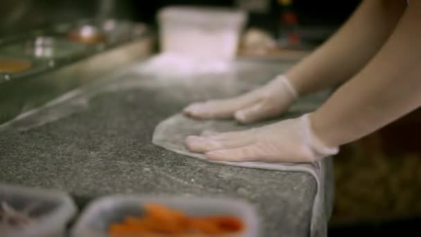 Повар выкатывает черное тесто по краю стола в ресторане — стоковое видео